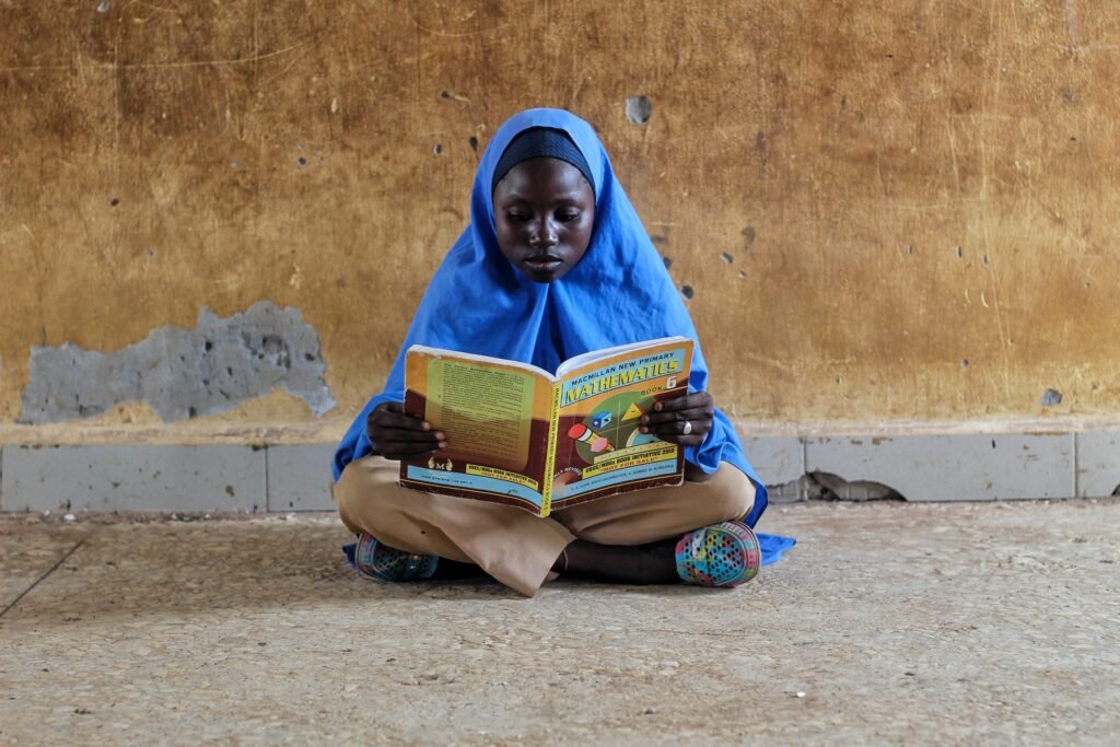 Young Girl Sitting and Reading a Textbook